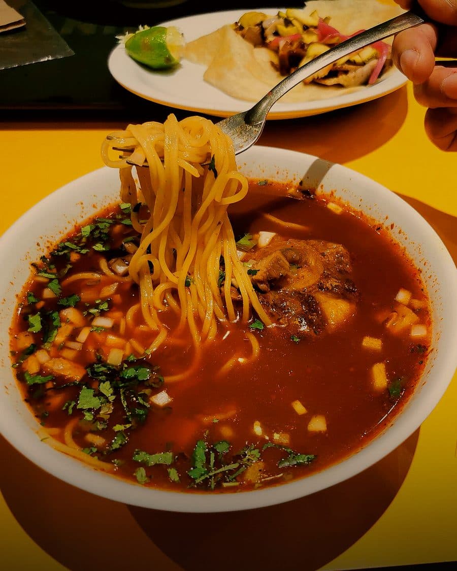 Tazón de birria ramen en consomé rojo con carne suave
